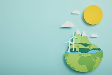 top view of paper cut planet with renewable energy sources on turquoise background, earth day concept clipart