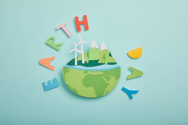 Üstten Görünüm kağıt gezegen yenilenebilir enerji kaynakları ve renkli kağıt mektuplar turkuaz arka planda, dünya gün kavramı kesmek.