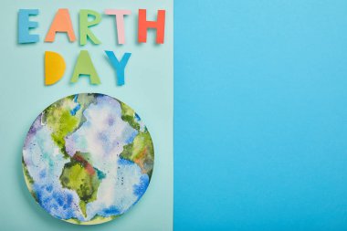 top view of colorful paper letters and planet picture on green and blue background, earth day concept clipart