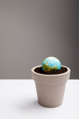 planet model placed in flowerpot with soil on table surface, earth day concept clipart