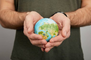 man holding planet model on grey background, earth day concept clipart