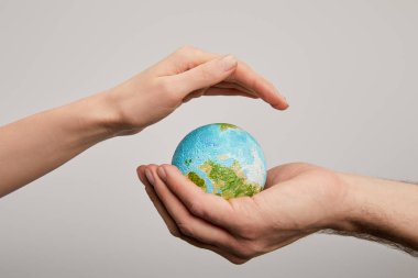 man and woman holding planet model on grey background, earth day concept clipart