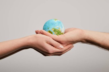 man and woman holding planet model on grey background, earth day concept clipart