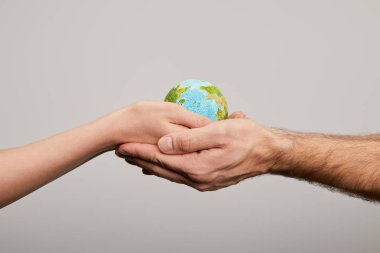 man and woman holding planet model on grey background, earth day concept clipart