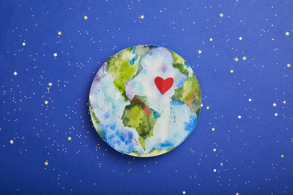 top view of planet picture with heart symbol on violet background with stars, earth day concept