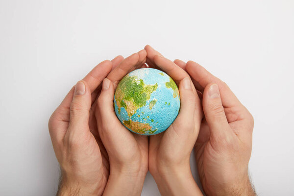 top view of woman and man holding planet model on grey background, earth day concept
