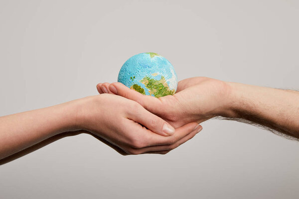 мужчина и женщина держат модель планеты на сером фоне, концепция Дня Земли

