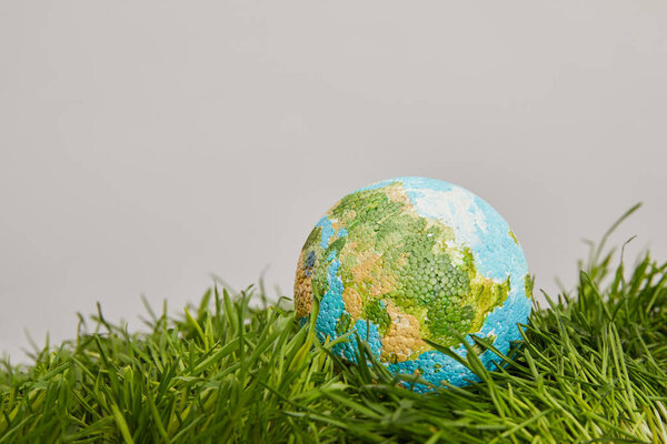 модель планеты размещена на зеленой поверхности травы, концепция земного дня
