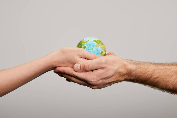 man and woman holding planet model on grey background, earth day concept