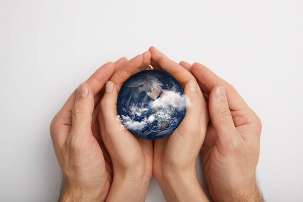 top view of man and woman holding planet model on grey background, earth day concept
