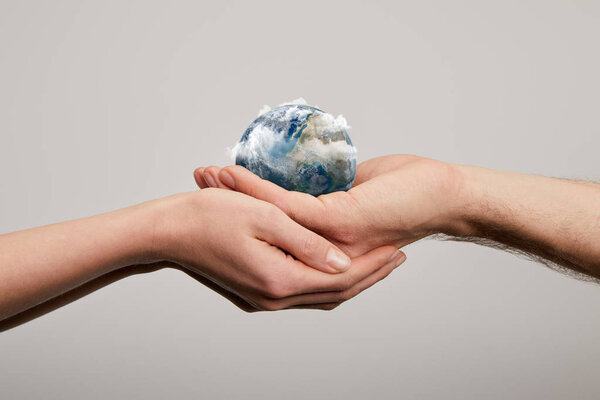 man and woman holding planet model on grey background, earth day concept
