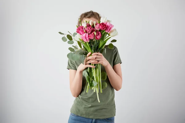 チューリップやグレーに分離された顔の前でバラの花束を持って女の子 — ストック写真