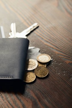 selective focus of leather wallet, keys, cheque and coins on wooden table clipart