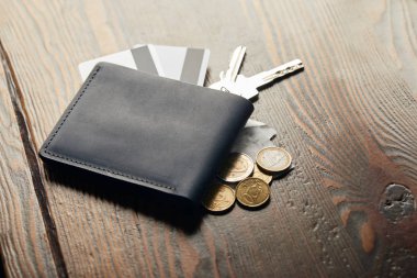 deri cüzdan, anahtarlar, Çek, sikke ve ahşap masa üzerinde kredi kartları