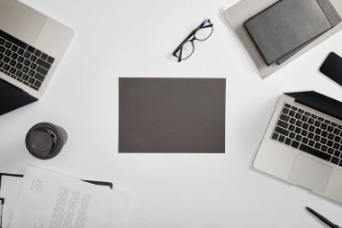 documet üstten görünüm Pano, kağıt bardak, dizüstü bilgisayarlar, kalem, defter, klasör, gözlük ve gri kağıt üzerinde 