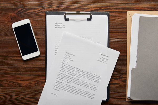 верхний вид документации в буфер обмена, смартфон и папка на столе
 