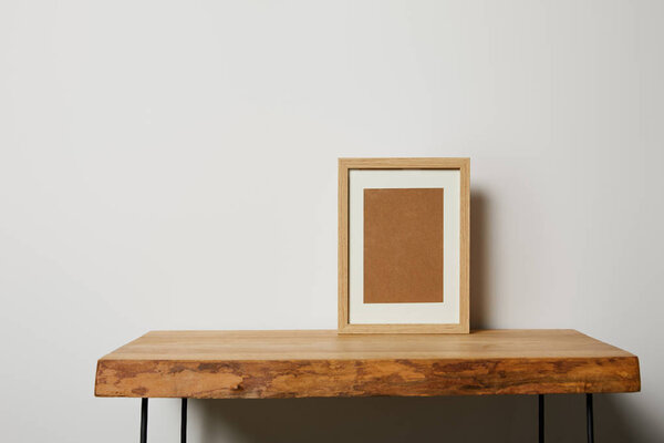 blank square frame on wooden textured table at home