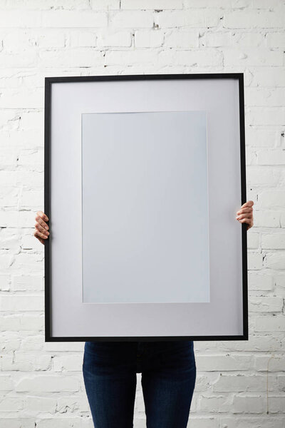 woman covering face while holding blank black frame in hands