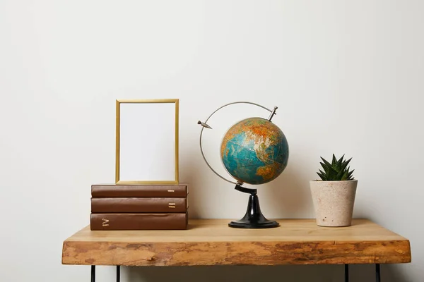 Frame on books near globe and green plant in pot — Stock Image Frame Books Globe Green Plant Pot Royalty Free Stock Images