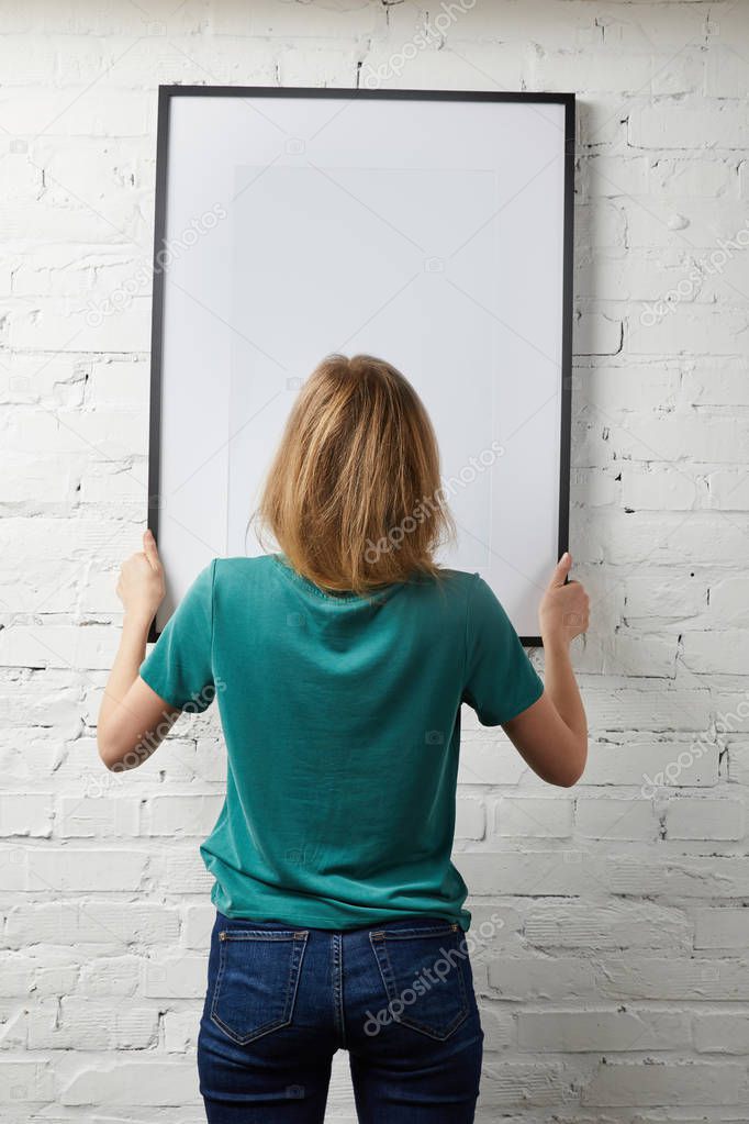back view of woman holding mock up poster with black frame