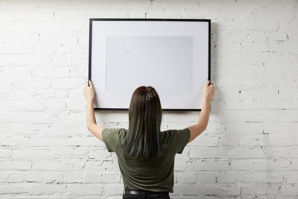 back view of woman holding blank black frame in hands 