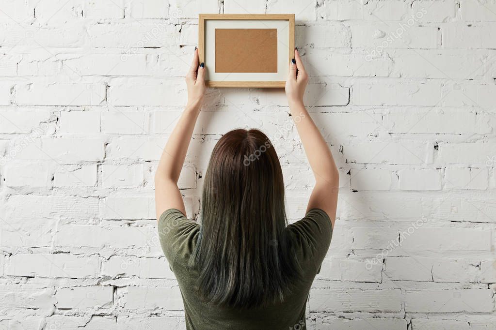 back view of woman holding blank brown frame in hands