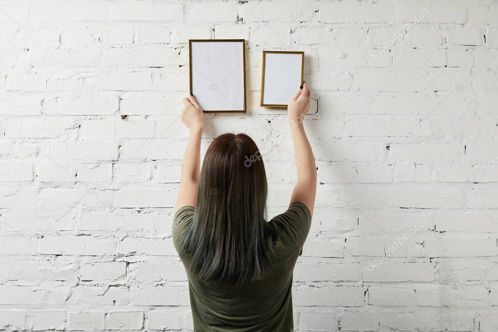 back view of woman holding blank square frame in hands