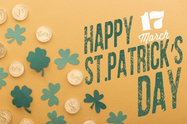 top view of golden coins with dollar signs near green shamrocks and happy st patricks day lettering on orange background clipart
