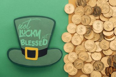 top view of golden coins near paper hat with not lucky just blessed lettering on green background clipart