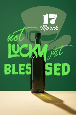 glass beer bottle with not lucky just blessed lettering on green background clipart