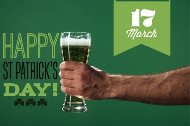 bir bardak bira ile köpük mutlu st yakınındaki tutan adam görünümü kırpılmış patricks günü yazı yeşil zemin üzerine
