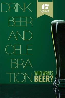 glass of beer with foam near drink beer and celebration lettering on green background clipart