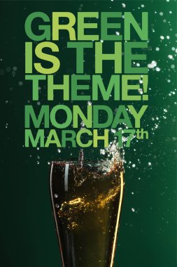 glass of beer with splash near green is the theme lettering on green background clipart