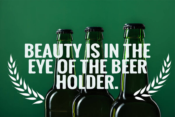 beer bottles near beauty is in the eye of the beer holder lettering on green background