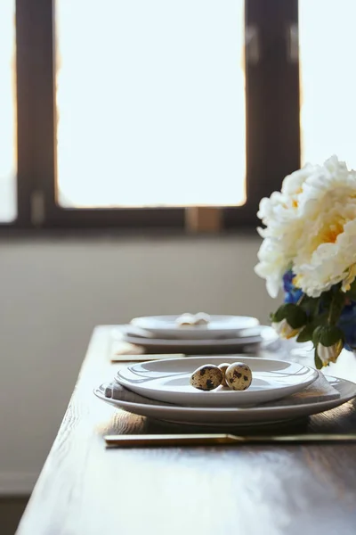 Selektiv Fokus För Vaktelägg Vita Tallrikar Nära Blommor Träbord Hemma — Stockfoto