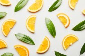 Top view of orange slices and green leaves on white background