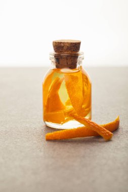 Glass bottle of essential oil with orange pieces on white background clipart