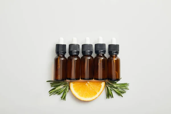 Top View Bottles Essential Oil Orange Slice Rosemary Grey Background — Stock Photo, Image