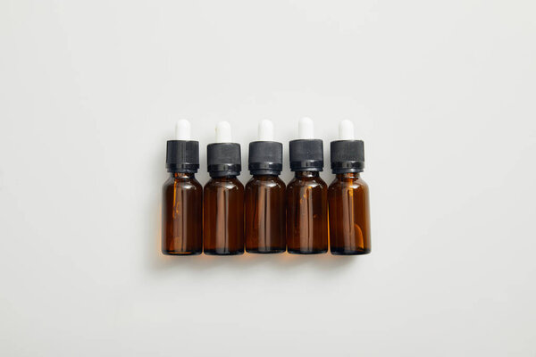 Top view of brown bottles with essential oil on grey background