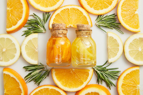 Flat lay with glass bottles and citrus slices with rosemary on white background