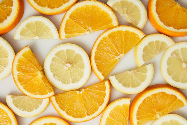 Вид сверху на оранжевый и лимонный ломтики на белом фоне

