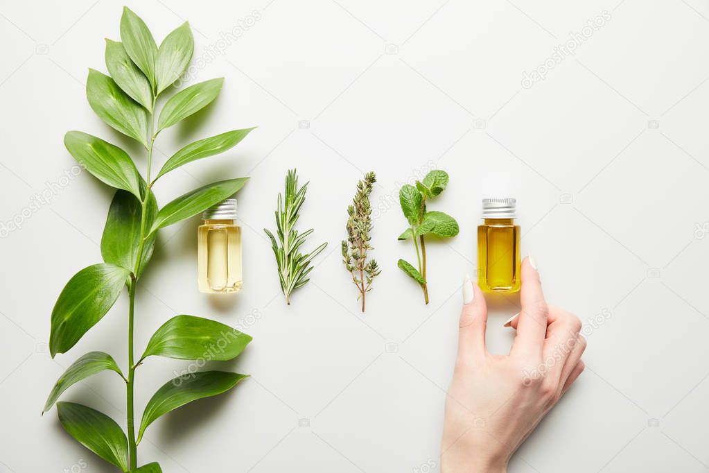 Cropped view of woman holding bottle with essential oil on white background