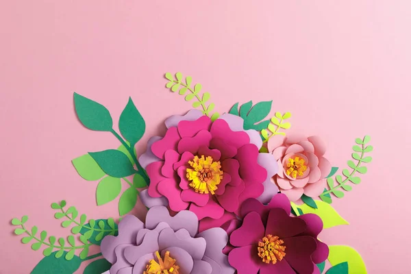 在粉红色背景上的五颜六色的纸花和绿叶的顶部视图 — 图库照片
