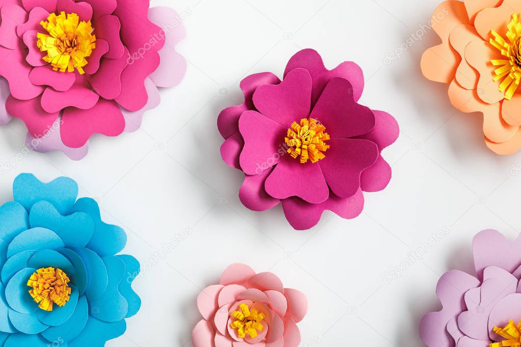 top view of colorful paper flowers on grey background
