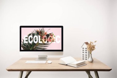yeşil yaprak ve ahşap masa üzerinde monitörde ekolojik yazı ile bilgisayar