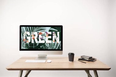 yeşil yaprakları ve ahşap masa üzerinde monitörde yeşil yazı ile bilgisayar