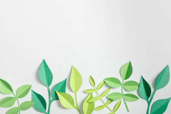 top view of green paper plants with leaves on grey background