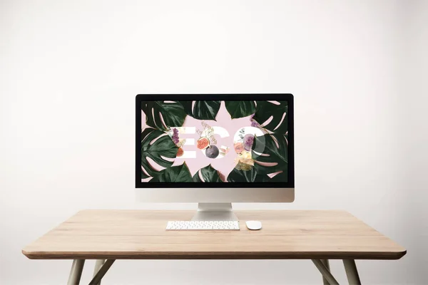 电脑与绿色的怪物叶和在木桌显示器上的生态字母 — 图库照片