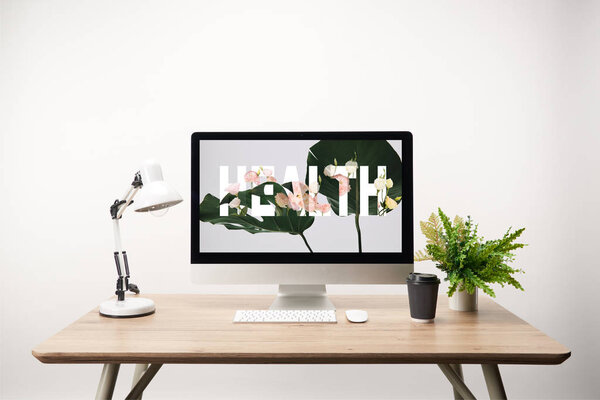 computer with green leaves and health lettering on monitor on wooden desk