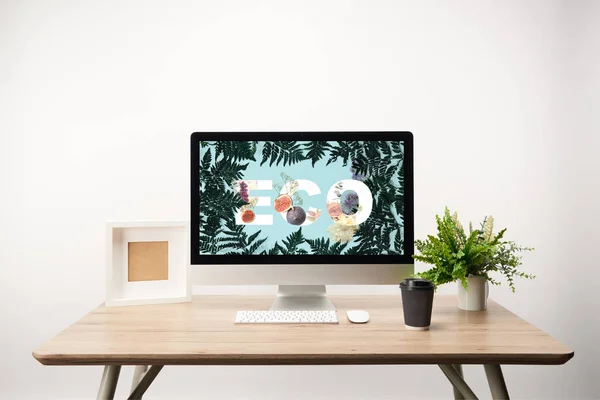 computer with green leaves and eco lettering on monitor on wooden desk